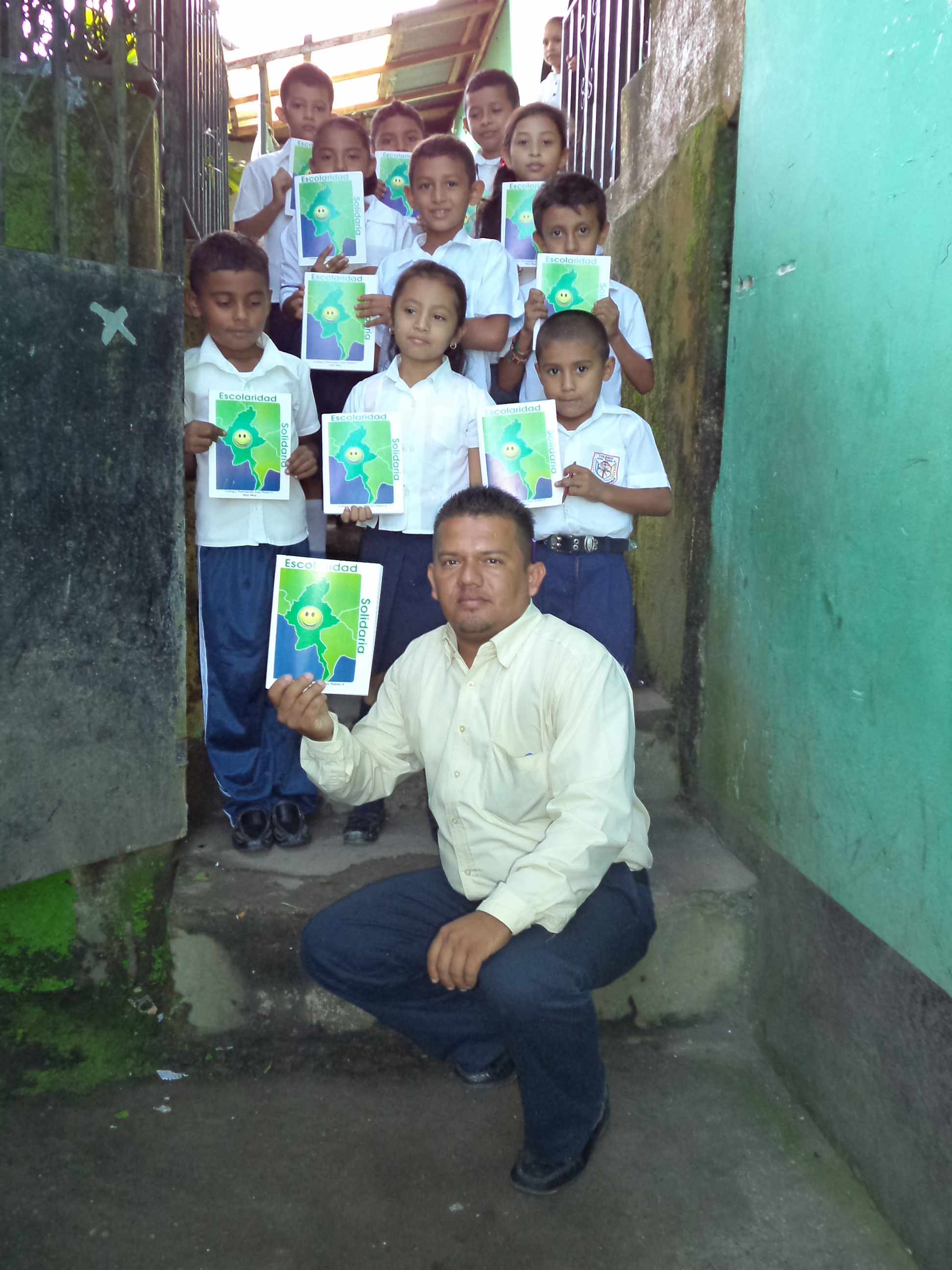Los niños con su profesor muestran las libretas de Escolaridad Solidaria